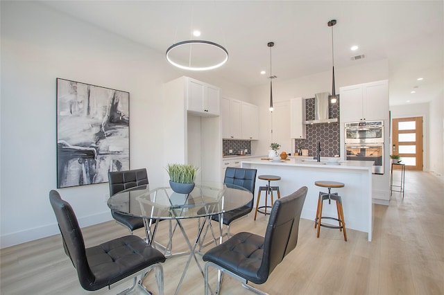 dining space with sink and light wood-type flooring