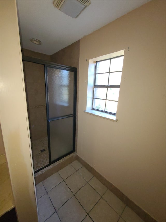 bathroom with tile patterned floors and a shower with door