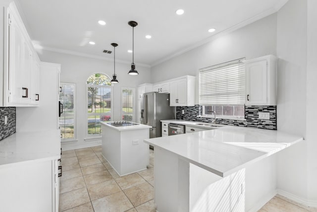 kitchen with appliances with stainless steel finishes, a kitchen island, pendant lighting, white cabinets, and kitchen peninsula