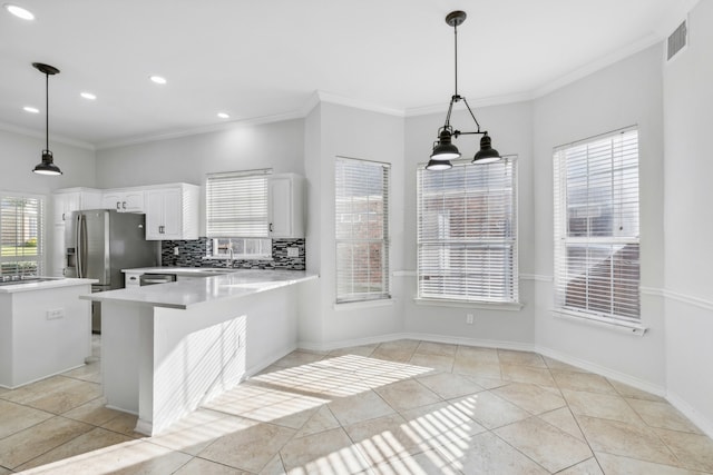 kitchen featuring tasteful backsplash, white cabinets, hanging light fixtures, and ornamental molding