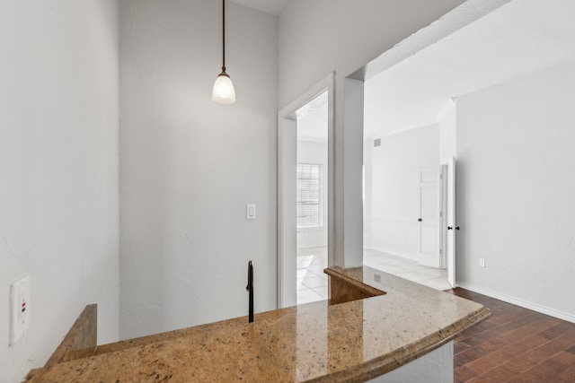 kitchen with light stone countertops, decorative light fixtures, and hardwood / wood-style flooring