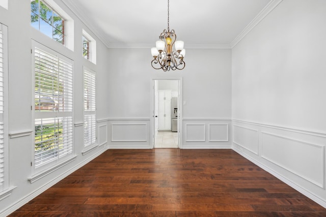 empty room with ornamental molding, dark hardwood / wood-style floors, and an inviting chandelier