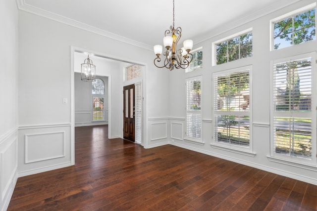 unfurnished dining area with dark hardwood / wood-style flooring, crown molding, and a notable chandelier