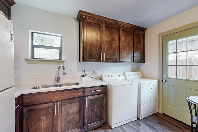 laundry room featuring a healthy amount of sunlight, washing machine and dryer, wood-type flooring, and sink