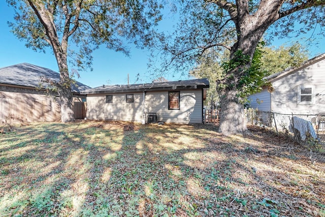 rear view of house featuring central AC and a yard