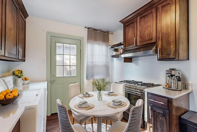 kitchen with washing machine and dryer, dark hardwood / wood-style flooring, dark brown cabinets, and high end stainless steel range oven