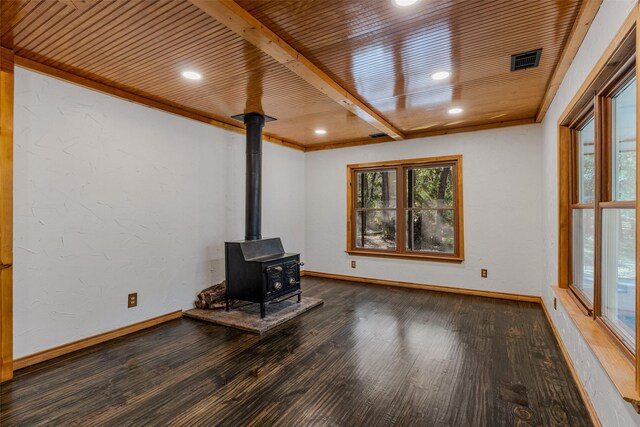 unfurnished living room featuring a wood stove, beamed ceiling, wooden ceiling, and dark hardwood / wood-style floors