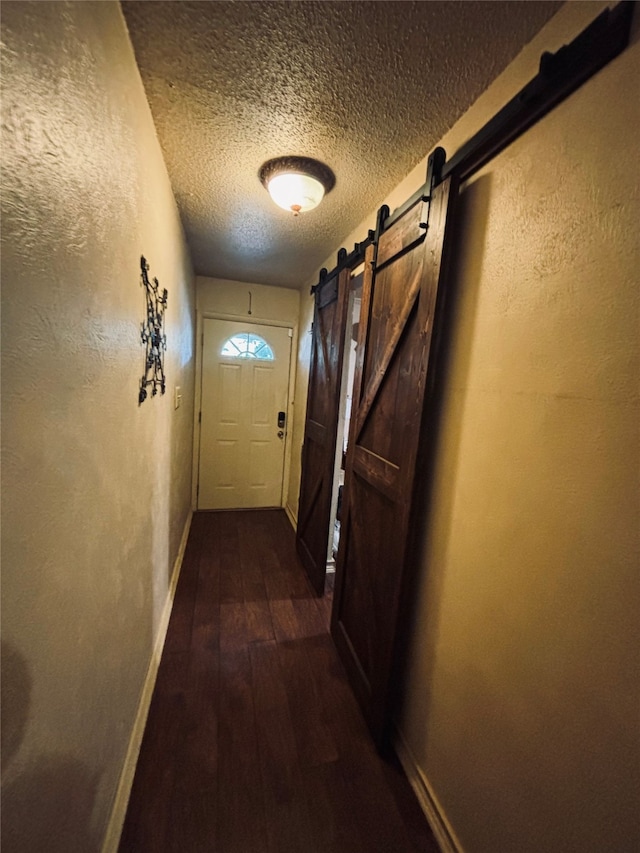 doorway to outside featuring a barn door, dark hardwood / wood-style flooring, and a textured ceiling