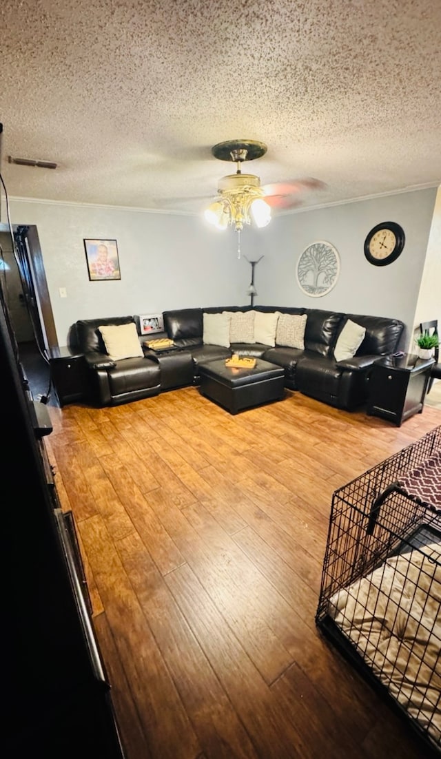 living room featuring wood-type flooring, a textured ceiling, and ceiling fan