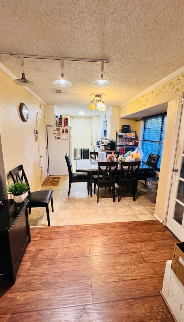 dining area featuring wood-type flooring, a textured ceiling, ceiling fan, and ornamental molding