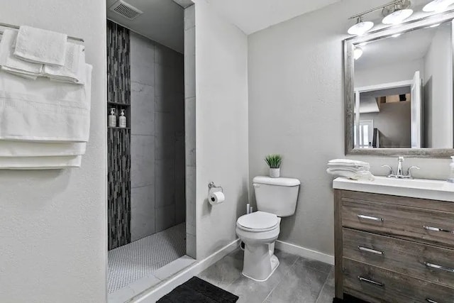 bathroom with tile patterned flooring, a tile shower, vanity, and toilet