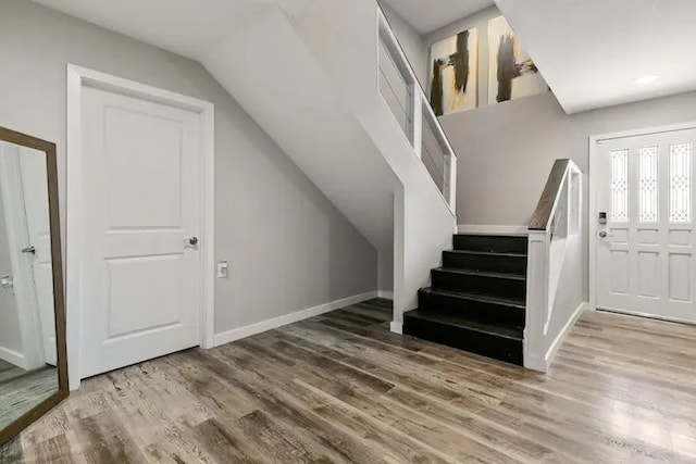 stairs with hardwood / wood-style flooring and vaulted ceiling