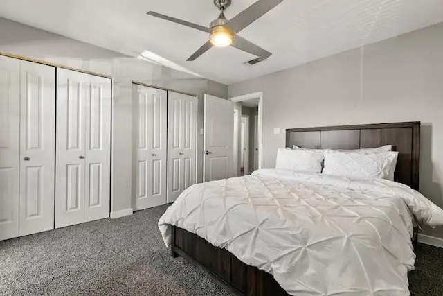 carpeted bedroom with ceiling fan and multiple closets