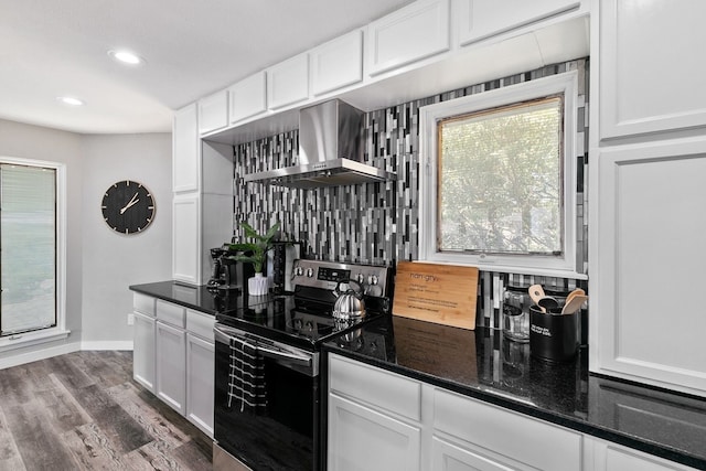 kitchen with tasteful backsplash, white cabinets, wall chimney exhaust hood, and electric range oven