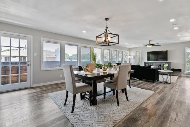 dining space with ceiling fan with notable chandelier, light wood-type flooring, and a wealth of natural light