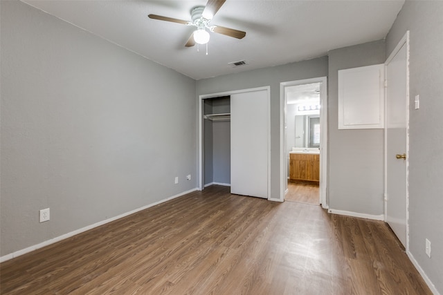 unfurnished bedroom with hardwood / wood-style flooring, ceiling fan, ensuite bathroom, and a closet