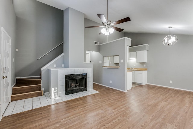 2240 Tarpley Rd Unit 462, Carrollton, TX 75006 - unfurnished living room with stairs, ceiling fan, light wood-style floors, a chandelier, and a tiled fireplace