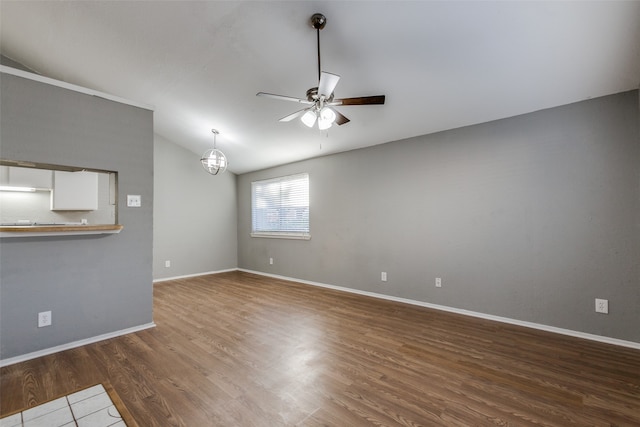 unfurnished living room featuring hardwood / wood-style floors, ceiling fan with notable chandelier, and lofted ceiling