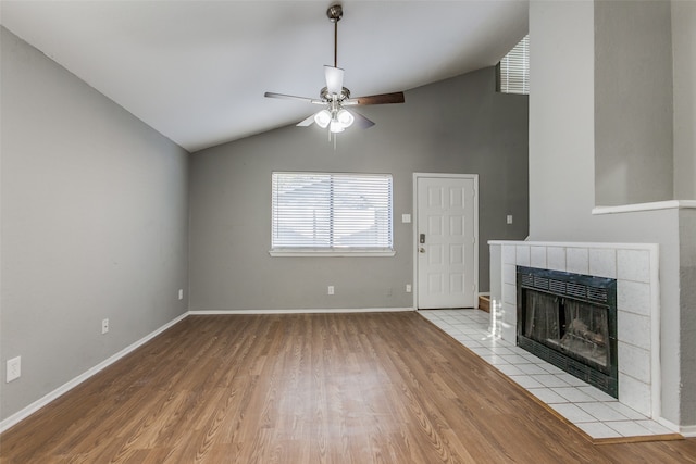 unfurnished living room with a tile fireplace, light wood-type flooring, ceiling fan, and lofted ceiling