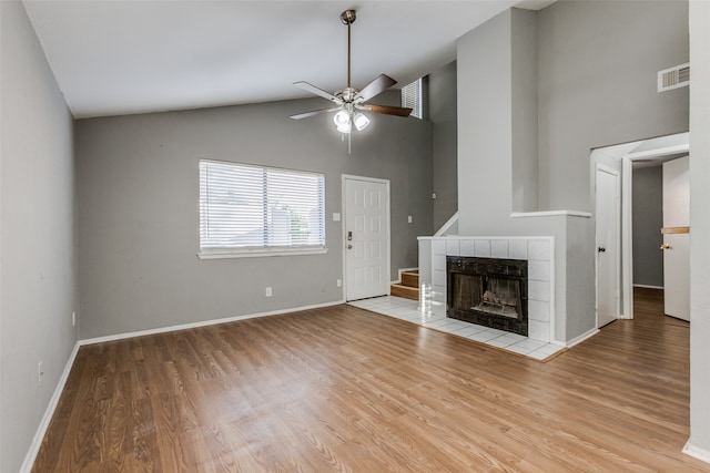 unfurnished living room featuring ceiling fan, light hardwood / wood-style floors, a fireplace, and high vaulted ceiling