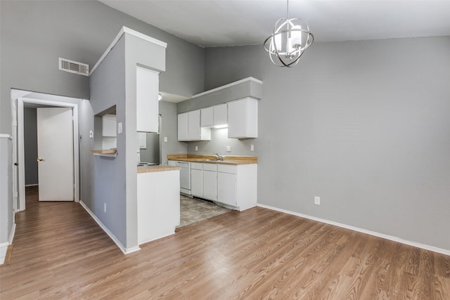 kitchen featuring dishwasher, wood counters, white cabinets, hanging light fixtures, and light hardwood / wood-style flooring