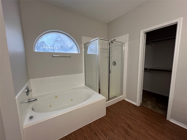 bathroom with wood-type flooring, a textured ceiling, and shower with separate bathtub