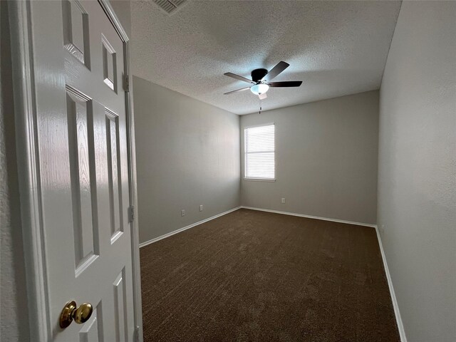 unfurnished room with dark colored carpet, ceiling fan, and a textured ceiling