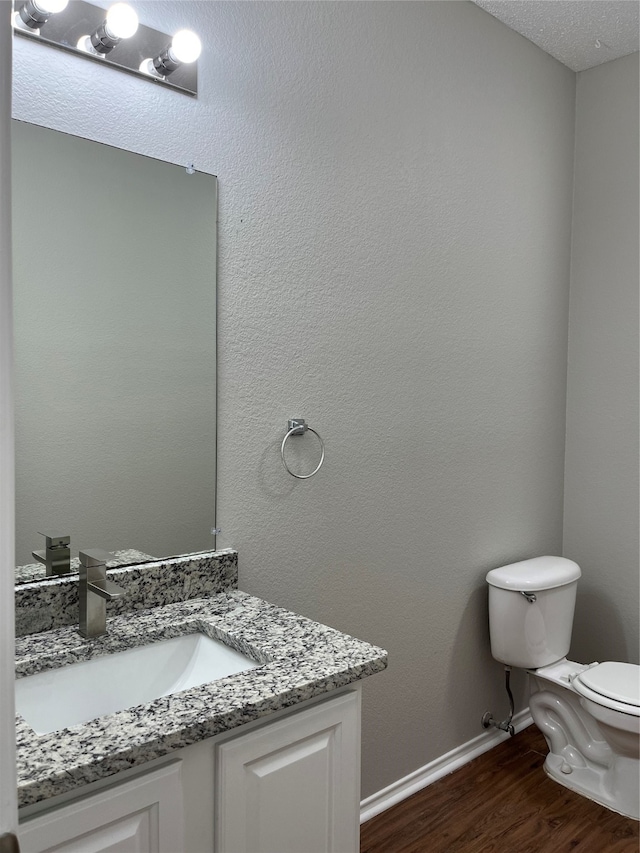 bathroom featuring a textured ceiling, vanity, hardwood / wood-style flooring, and toilet