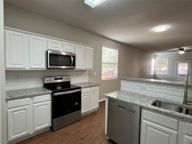 kitchen with dark hardwood / wood-style flooring, stainless steel appliances, white cabinetry, and sink