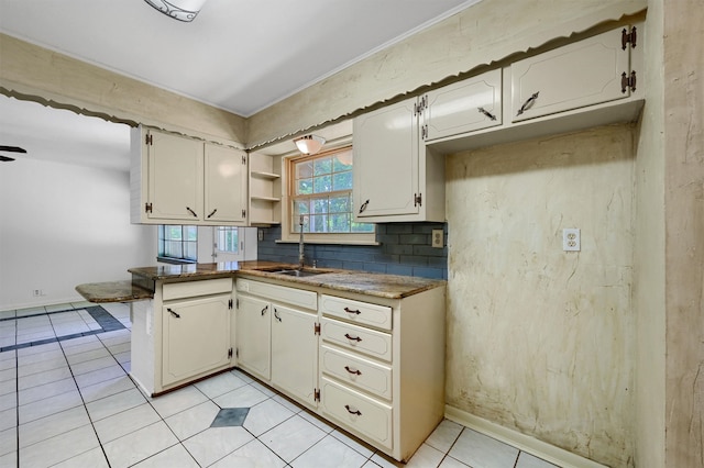 kitchen featuring light tile patterned flooring, sink, white cabinetry, and backsplash