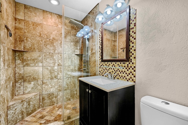 bathroom featuring a tile shower, vanity, and toilet