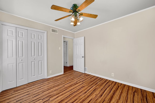 unfurnished bedroom with ceiling fan, a closet, ornamental molding, and hardwood / wood-style flooring