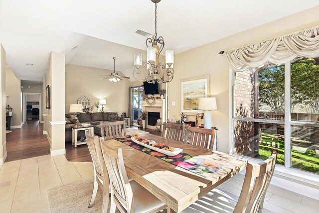 dining space with ceiling fan with notable chandelier, vaulted ceiling, and light hardwood / wood-style flooring