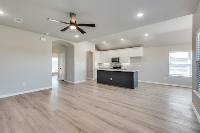 kitchen with light hardwood / wood-style flooring, white cabinetry, a kitchen island with sink, and ceiling fan