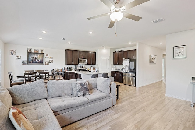 living room with ceiling fan and light wood-type flooring