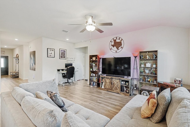 living room with ceiling fan, light hardwood / wood-style floors, and vaulted ceiling