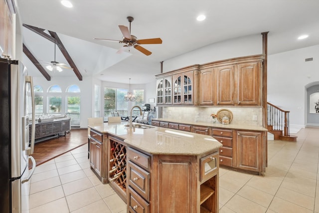 kitchen with sink, an inviting chandelier, vaulted ceiling with beams, stainless steel fridge with ice dispenser, and a center island with sink