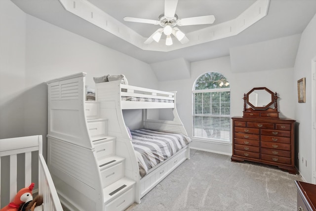 carpeted bedroom featuring a raised ceiling, vaulted ceiling, and ceiling fan