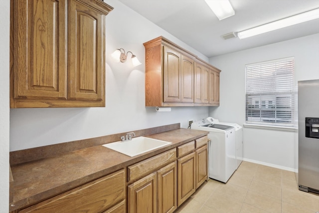 washroom featuring washing machine and dryer, sink, light tile patterned floors, and cabinets