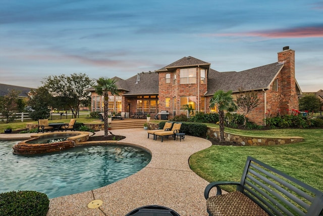 pool at dusk with a lawn, an in ground hot tub, and a patio