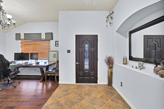 entrance foyer featuring a textured ceiling, a chandelier, dark wood-type flooring, and vaulted ceiling