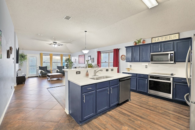 kitchen featuring sink, hanging light fixtures, vaulted ceiling, blue cabinetry, and stainless steel appliances