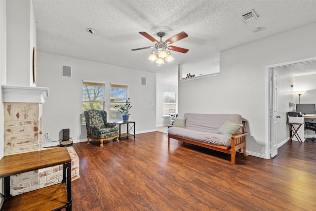 living room with dark hardwood / wood-style floors, ceiling fan, and a textured ceiling