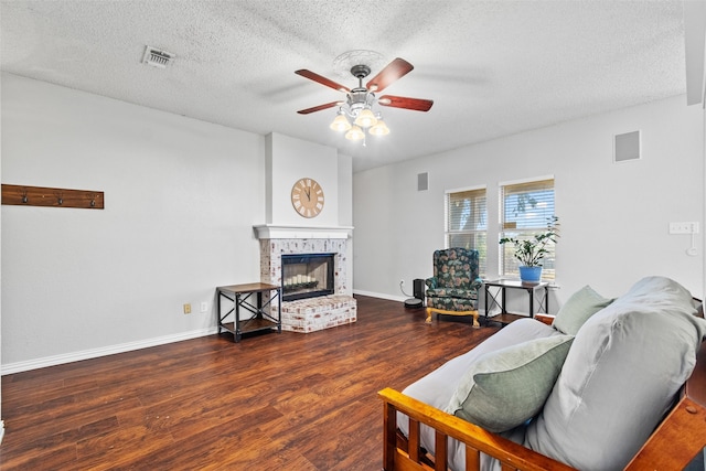 living room featuring a fireplace, a textured ceiling, dark hardwood / wood-style floors, and ceiling fan