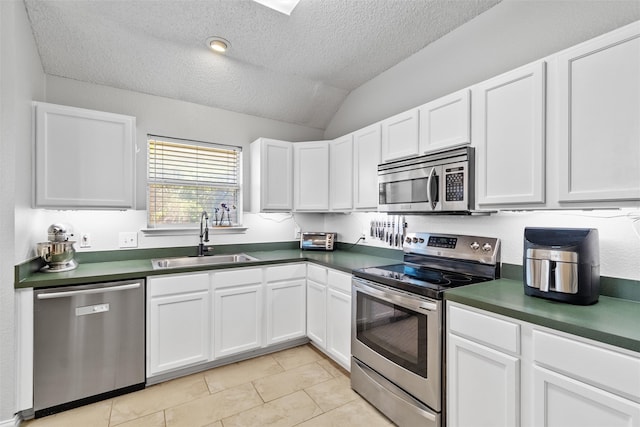 kitchen with white cabinets, stainless steel appliances, vaulted ceiling, and sink