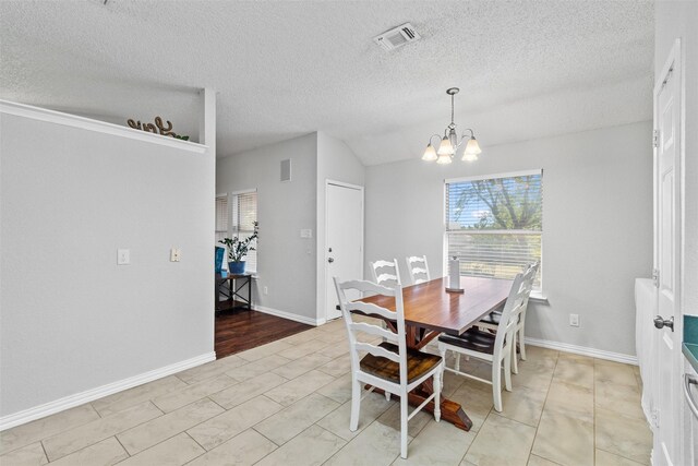 tiled dining area featuring an inviting chandelier, a textured ceiling, and vaulted ceiling