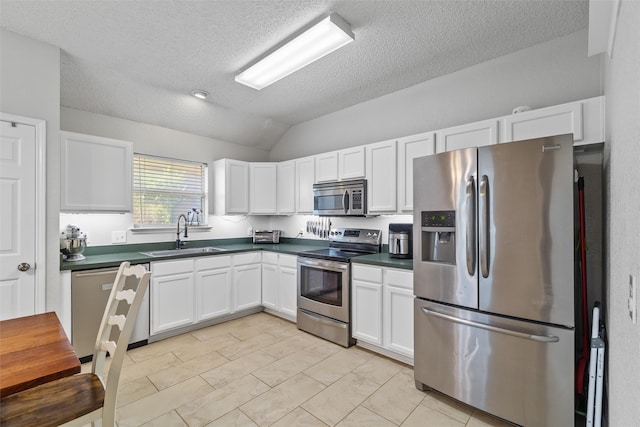 kitchen with white cabinets, stainless steel appliances, vaulted ceiling, and sink