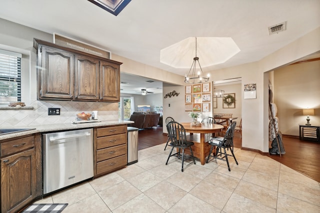 kitchen with a wealth of natural light, dishwasher, hanging light fixtures, and light hardwood / wood-style flooring