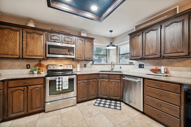 kitchen featuring stainless steel appliances, tasteful backsplash, light stone counters, pendant lighting, and light tile patterned flooring