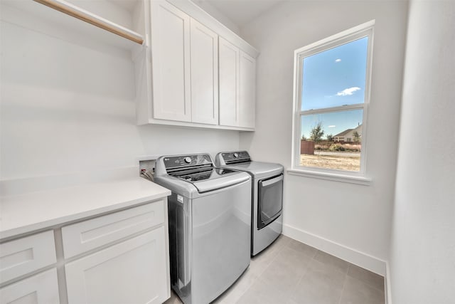 clothes washing area with cabinets, light tile patterned floors, and washer and dryer